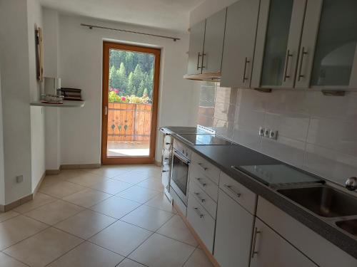 una cocina con fregadero y una puerta a un patio en Unterweg Hof, en Sarentino