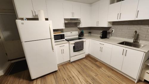 cocina con armarios blancos y nevera blanca en Charming East Van Hideaway - Near SkyTrain, en Vancouver