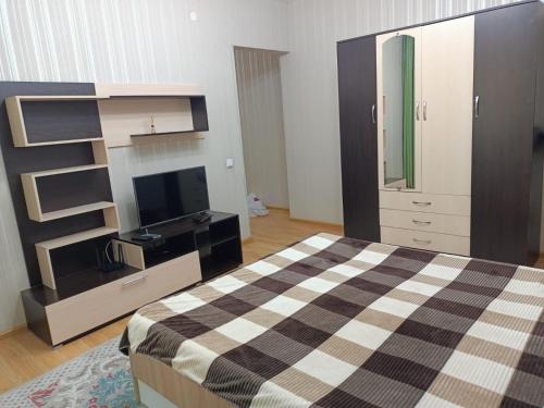 um quarto com uma cama, uma cómoda e uma televisão em Апартомент Алмалы напротив Алматы Арены em Almaty
