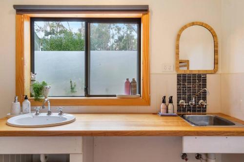 eine Badezimmertheke mit einem Waschbecken und einem Fenster in der Unterkunft Peaceful Bruny Island Shack in Dennes Point