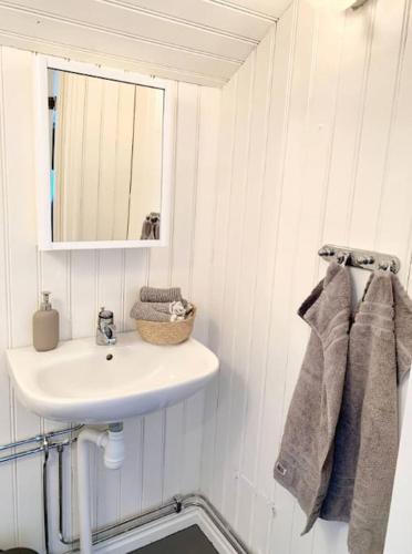 Baño blanco con lavabo y espejo en SeaSide en Hjälteby