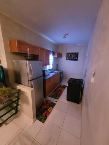 una pequeña cocina con nevera y encimera en #1 Jacaranda Vacation Home, en Spanish Town