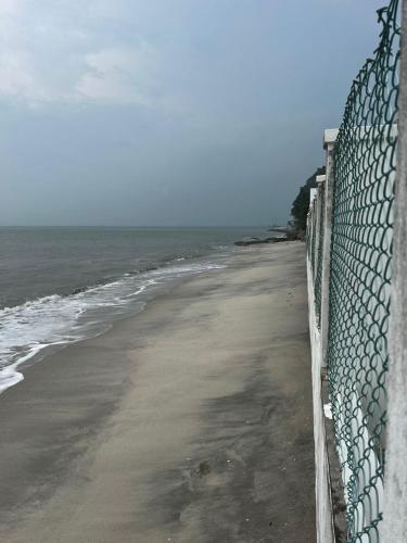a fence on a beach next to the ocean at The Beach Inn in Tanjung Bungah