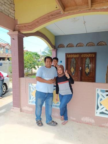 a group of three people standing in front of a house at Homestay D'Hiburan Kuala Rompin in Kuala Rompin