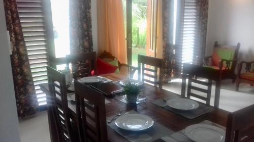 comedor con mesa de madera y sillas en Induruwa Cottage en Induruwa