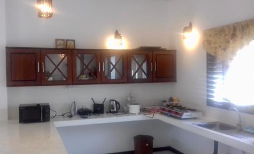 cocina con armarios de madera y encimera blanca en Induruwa Cottage en Induruwa