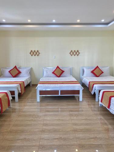a room with three beds with red pillows on them at Hoa Sua Hotel in Vung Tau