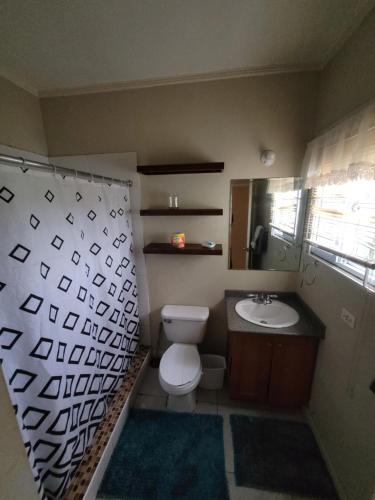 a bathroom with a toilet and a sink and a mirror at #1 Jacaranda Vacation Home in Spanish Town