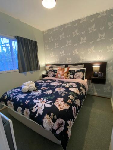 a bedroom with a bed with a floral bedspread at The Cozy Hutt Home in Upper Hutt