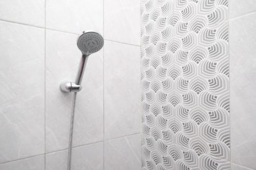 a shower with a shower head in a bathroom at DR Living Syariah Solo Mitra RedDoorz in Kadiporo