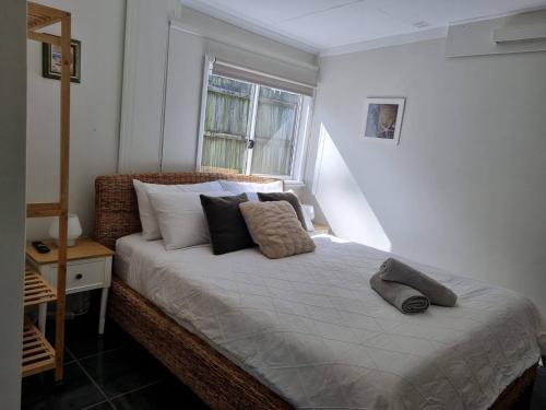 um quarto com uma cama com almofadas e uma janela em Redcliffe Homestay em Redcliffe