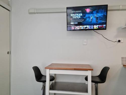 uma mesa com duas cadeiras e uma televisão na parede em Redcliffe Homestay em Redcliffe