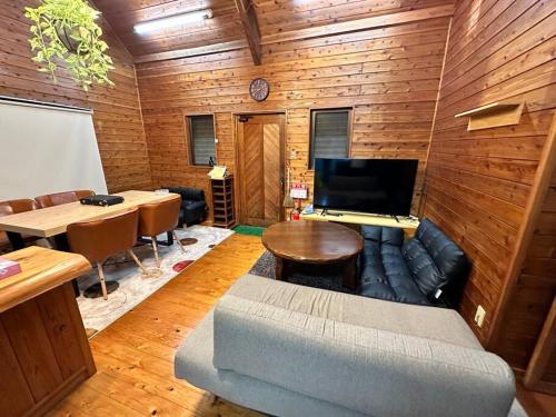 a room with a couch and a table and a tv at 貸別荘アソベルゴ in Okurabaru