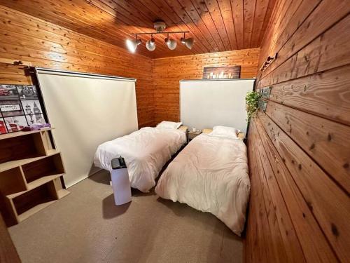 a bedroom with two beds in a room with wooden walls at 貸別荘アソベルゴ in Okurabaru