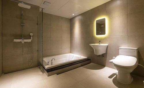 y baño con bañera, aseo y lavamanos. en Doksan 3S Hotel, en Seúl