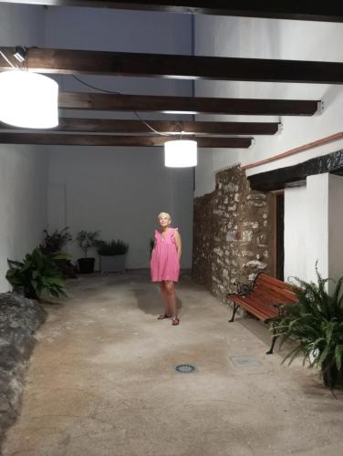 a woman in a pink dress standing in a room with a bench at Casa rural El Forn d'Alcudia de Veo in Alcudia de Veo