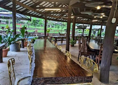 a large wooden table and chairs in a restaurant at Balay Ni Tatay Farm Resort by Cocotel in Babatngon
