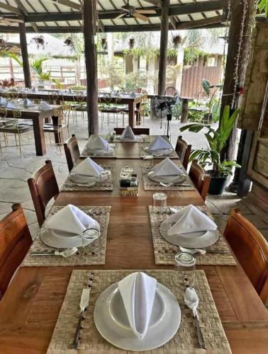 a wooden table with white plates and napkins on it at Balay Ni Tatay Farm Resort by Cocotel in Babatngon
