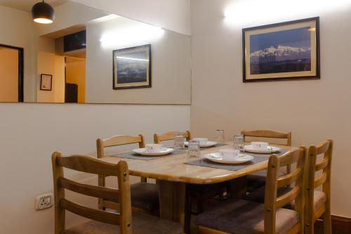 uma mesa de jantar com cadeiras e uma mesa de madeira em Red Panda Apartment em Darjeeling