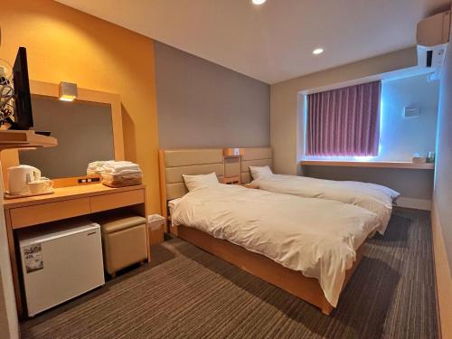 a hotel room with a bed and a desk and a window at Kansai Seaside Hotel in Kaizuka