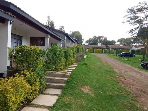 a house with some bushes and stairs next to a yard at Riverside 001 in Nanyuki