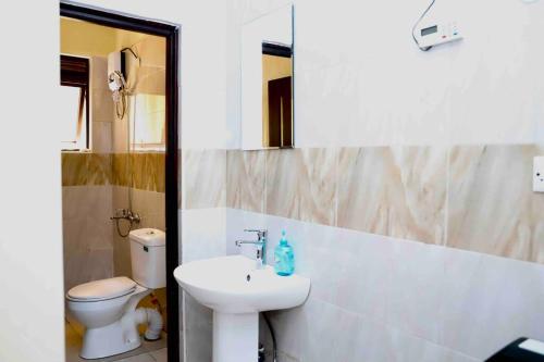 ein Badezimmer mit einem Waschbecken, einem WC und einem Spiegel in der Unterkunft Chill and Stay in Kampala