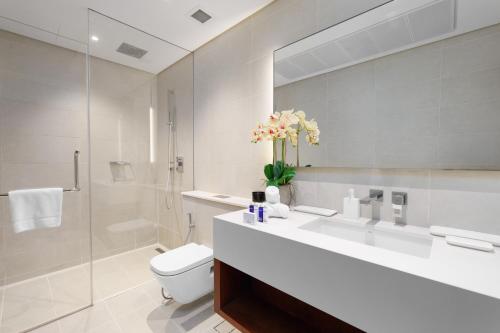a bathroom with a sink and a toilet and a mirror at Maison Privee - Modern Luxury Apt with Spectacular Dubai Marina Vws in Dubai