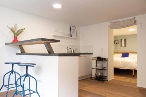 a kitchen and living room with a bed and stools at City Apartment Dornbirn, Hongkong 1 in Dornbirn
