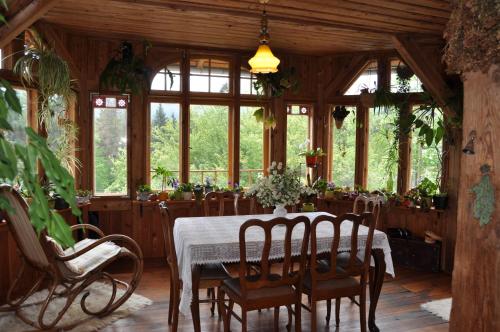 een eetkamer met een tafel, stoelen en ramen bij Villa Nostalgia in Szklarska Poręba