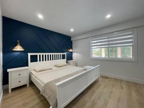 a bedroom with a white bed and a blue wall at Luxury Smart Home ~ Perfect Getaway Resort/Sleeps 14 in Langley