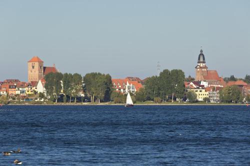 a sailboat on the water in front of a city at Seehotel Ecktannen in Waren