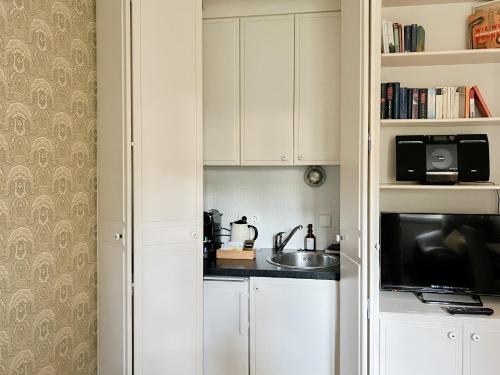 a kitchen with white cabinets and a sink and a microwave at von Deska Townhouses - Ivy House in Hamburg