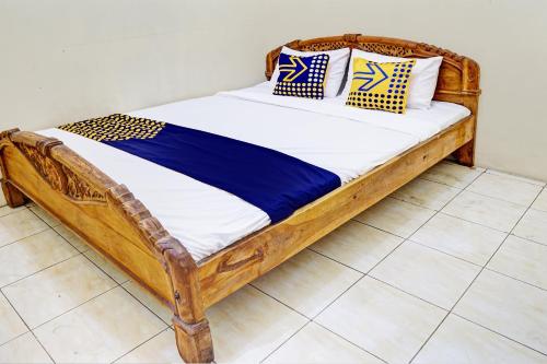 ein Holzbett mit Kissen darauf in einem Zimmer in der Unterkunft OYO 93108 Homestay H Syarif Syariah – RA Kartini in Gresik