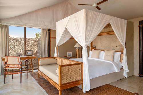 a bedroom with a canopy bed and a desk at The Outpost Al Barari in Mesaieed