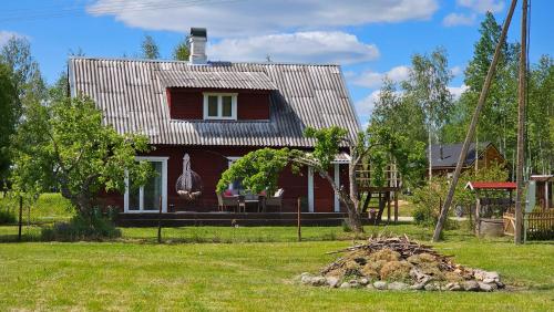 a small red house with a roof on a yard at Metsavahi puhketalu in Kaevussaare