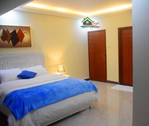 a bedroom with a large bed with a blue blanket at Bright cozy APT in the heart of Naguru in Kampala