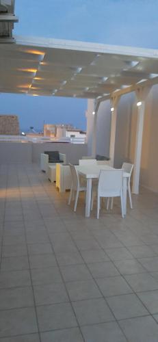 a patio with white tables and chairs on a roof at Apartaments "Le vele 1" in Pachino