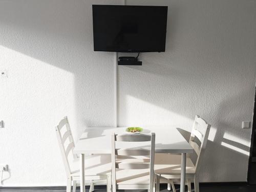 une table et des chaises blanches avec une télévision murale dans l'établissement Gemütliches Apartment Wuppertal, à Wuppertal