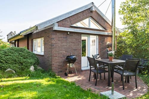 a brick house with a grill and a table and chairs at Ferienhaus in Noer