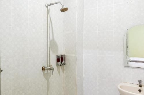 a shower with a glass door in a bathroom at Global Inn Syariah Mitra RedDoorz near Juanda T1 Airport in Semampir