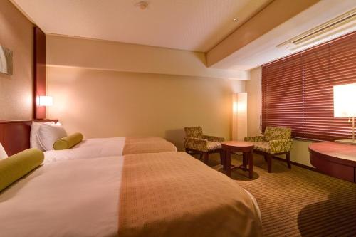 a hotel room with a bed and a desk and chairs at 焼津グランドホテル in Hanazawa