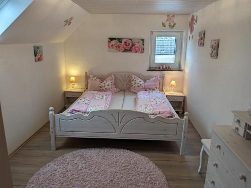 a bedroom with a white bed with pink pillows and a rug at Huus Meta in Krummhörn