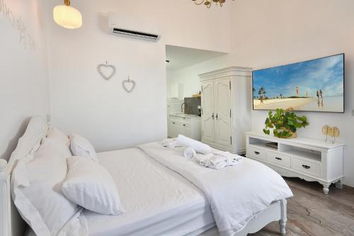 a white bedroom with a white bed and a tv at סוויטות רומאנס - סוויטות מהממות לזוגות ומשפחות in Metulla