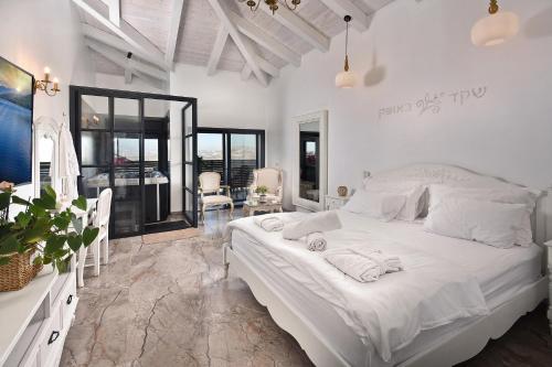 a white bedroom with a large bed with towels on it at סוויטות רומאנס - סוויטות מהממות לזוגות ומשפחות in Metulla