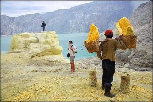 two people standing on rocks near a body of water at Dannu's Homestay Ijen and Bromo Tour in Banyuwangi