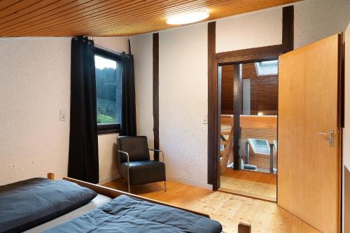 1 dormitorio con 2 camas, silla y ventana en Ferienhaus Schwarzwaldleben en Seebach