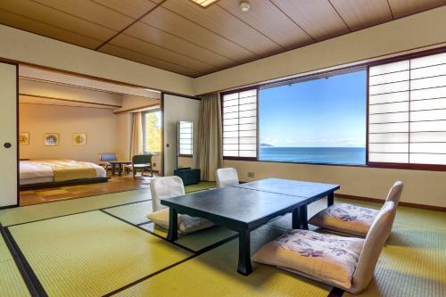 a room with a table and chairs and a bedroom at 焼津グランドホテル 