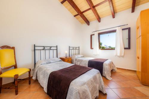 um quarto com 2 camas, uma cadeira e uma janela em Casa Coral - Cala Bona em Cala Bona