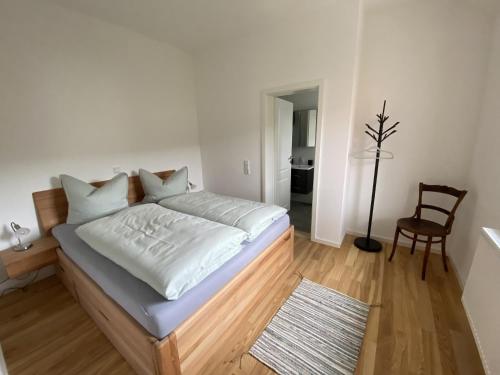 ein Schlafzimmer mit einem Bett mit weißer Bettwäsche und einem Stuhl in der Unterkunft Sand 68 in Steinau an der Straße