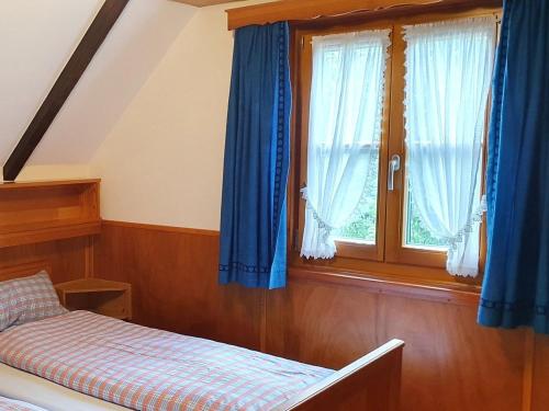 a bedroom with blue curtains and a bed and a window at Das Häusle in Neubulach
